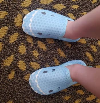 reviewer's child wearing blue slippers with cartoon shark faces
