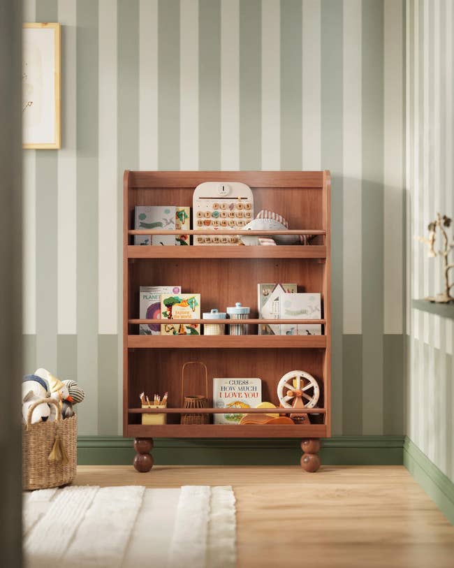 Wooden artifact support with assorted toys and books, including a artifact currency registry and puzzles, successful a cozy country with striped wallpaper