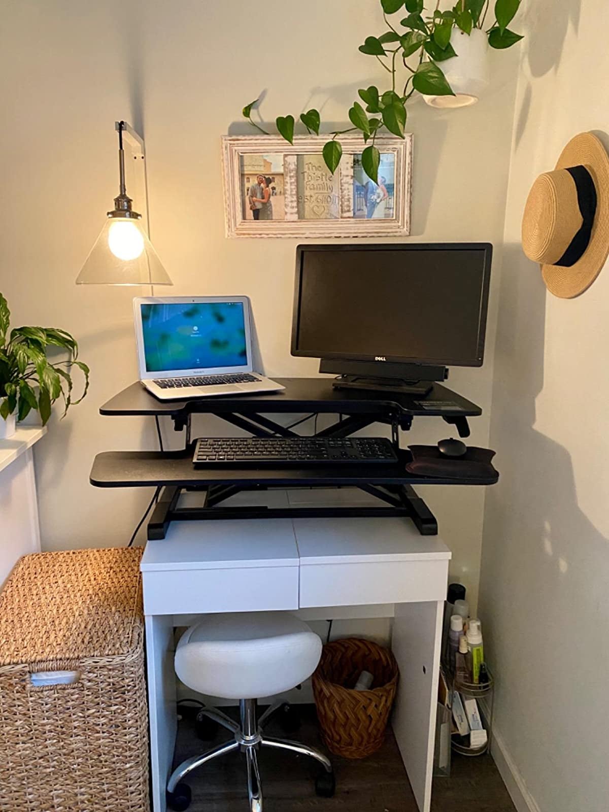 black standing desk converter with black monitor, laptop, and keyboard on small white desk