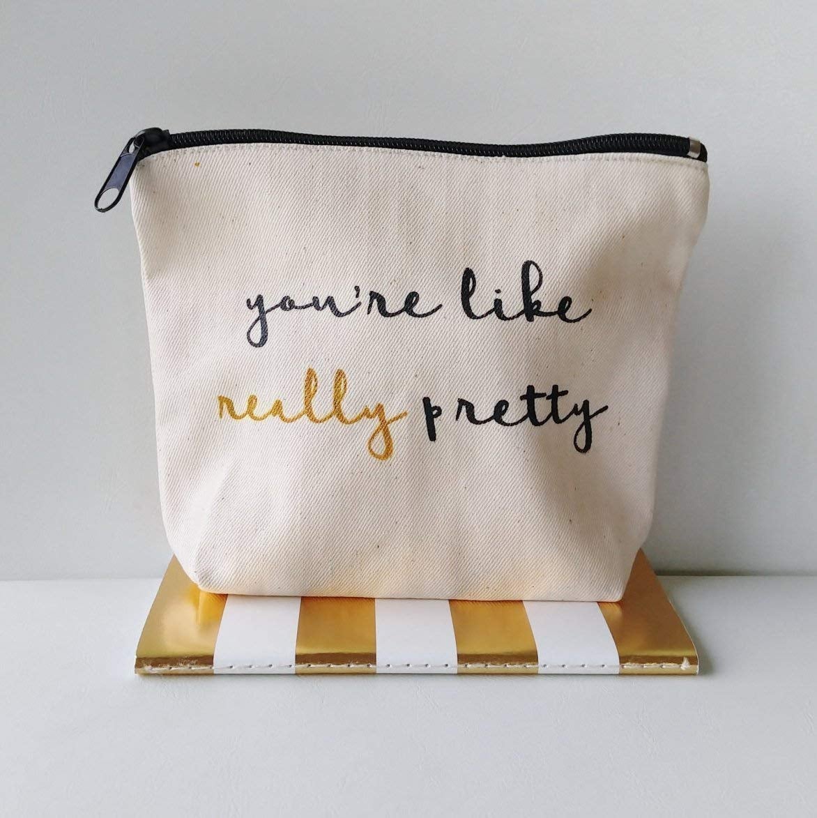 pouch that reads you're like really pretty in black and gold text