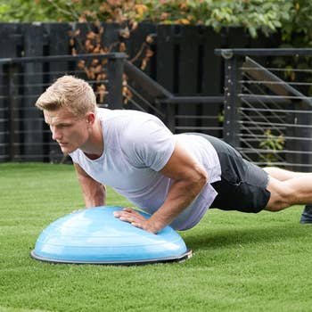 Person exercising outdoors, doing a push-up connected  a equilibrium  trainer successful  a garden