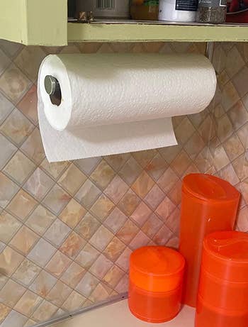 a reviewer photo of the paper towel holder mounted horizontally under a cabinet 