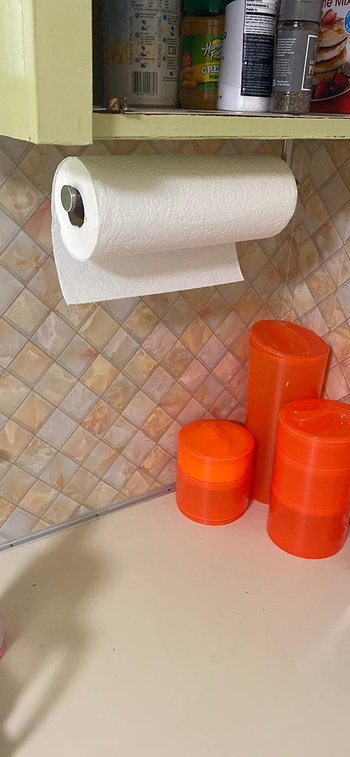 a reviewer photo of the paper towel holder mounted horizontally under a cabinet