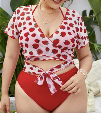 model in red bikini with short sleeve pink and red strawberry print crop top on top