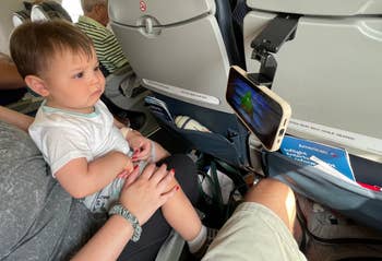 toddler watching a movie on a phone on a plane using a clip-on attachment