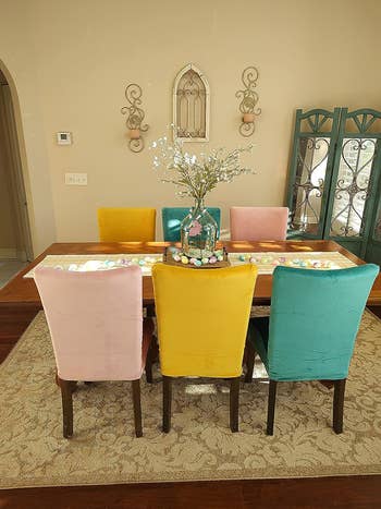 reviewer's dining room table with chairs in yellow, peacock green, and pink slipcovers