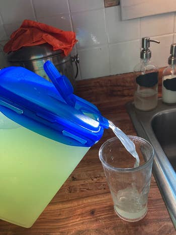 reviewer photo of lemonade being poured into a glass from the container