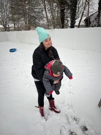 buzzfeed editor wearing a black puffer coat in the snow with her son