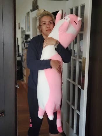 Reviewer holding the pink cat body pillow