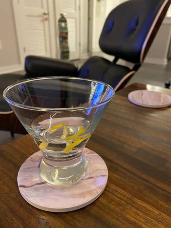 A reviewer photo of a marble coaster on a desk with a glass of water on it