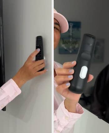 Person demonstrating a achromatic  TV distant    control, held against a wall, close-up view