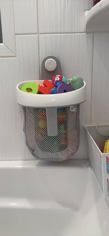 reviewers bath toy storage filled with toys and stuck to bathroom wall
