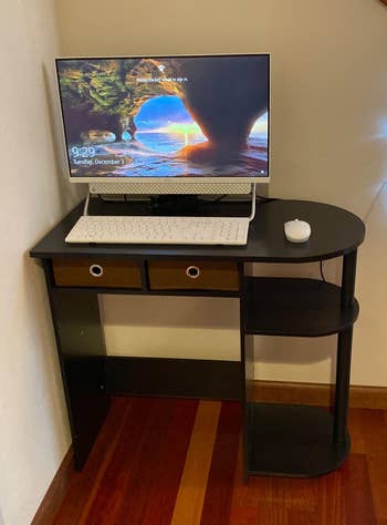 the desk with two drawers and two shelves, set up with a monitor and keyboard on top