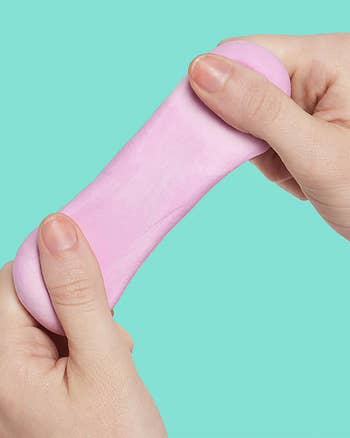 Hands stretching pinkish sensory putty