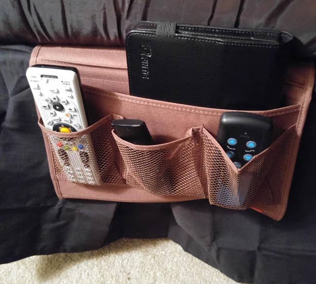Organizer with pockets holding a tablet, distant controls, and an physics instrumentality connected the broadside of a sofa