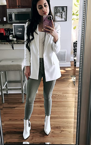 reviewer wearing the white blazer with a white top, green pants, and white boots