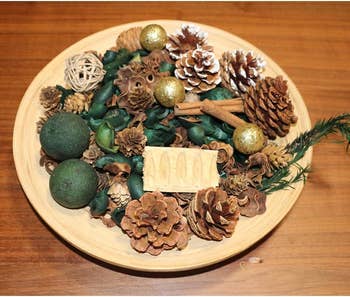 mix of pine needles, citrus, pine cones, and decorative pieces on plate