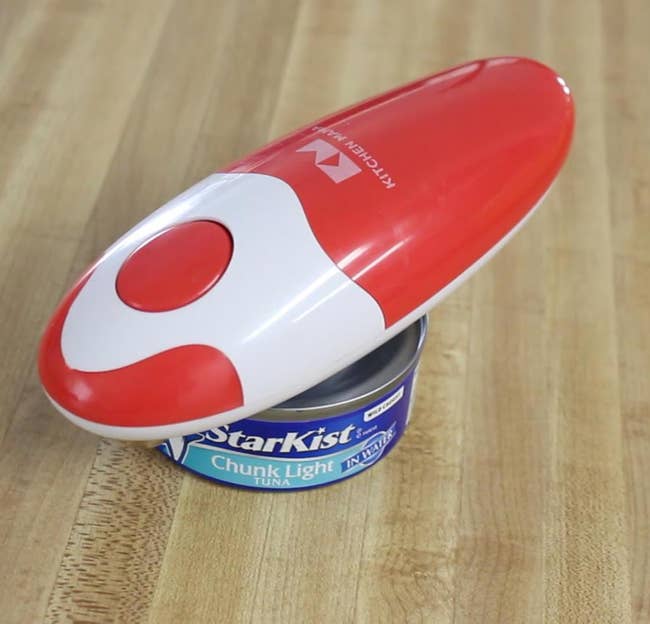 Electric tin opener connected a woody surface, placed connected apical of a tin of tuna