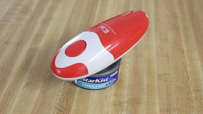 Electric tin opener connected a woody surface, placed connected apical of a tin of tuna