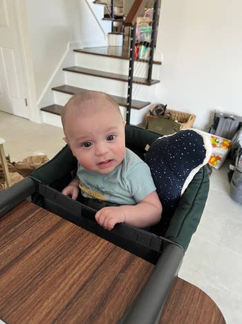 buzzfeed editor's baby sitting in the portable high chair