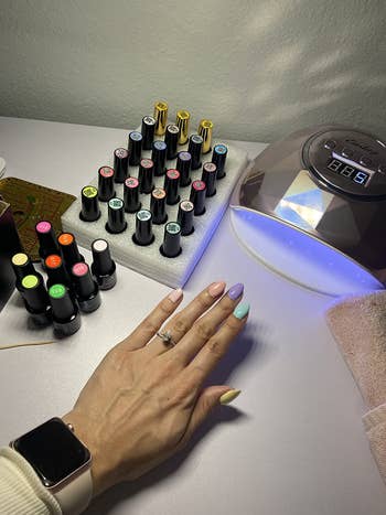 reviewer photo with colorful gel nails, showing hand in front of the lamp