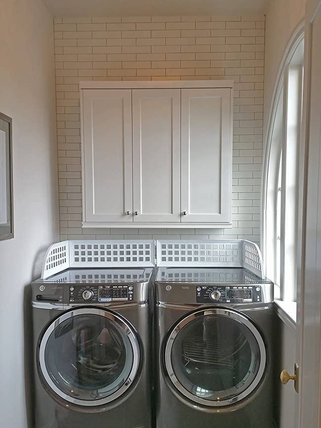 washer and dryer with plastic guards covering the top to prevent clothes from falling between machine and wall 