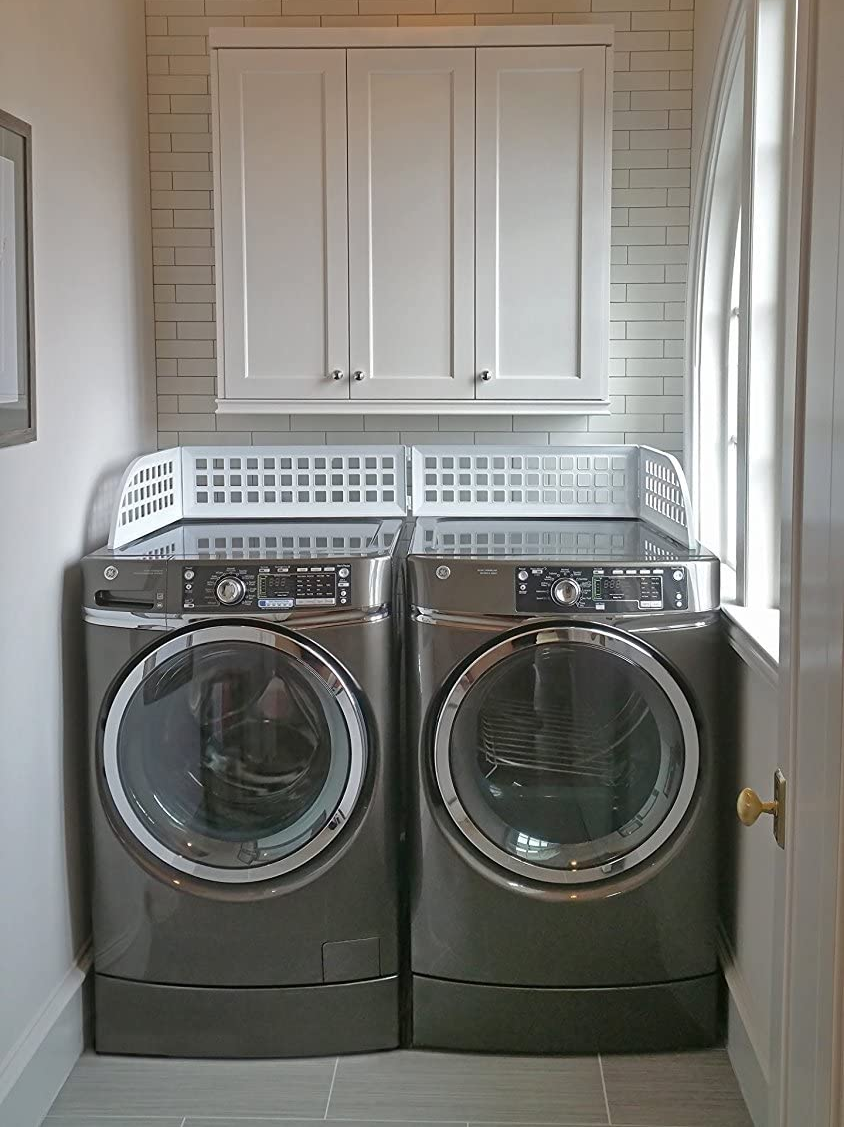 washer and dryer with plastic guards covering the top to prevent clothes from falling between machine and wall