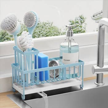 Sink organizer with brushes, sponge, scrubber, and soap dispenser, arranged adjacent   a faucet