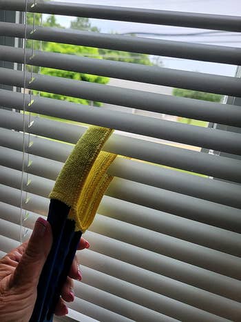 the yellow duster being used to clean blinds