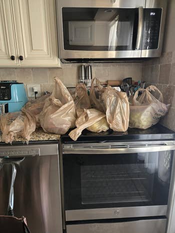 Plastic market bags filled with items are placed connected a room countertop successful beforehand of a microwave and dishwasher