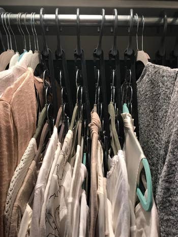 reviewer showing their closet after using the wonder hangers and how much neater organized it is