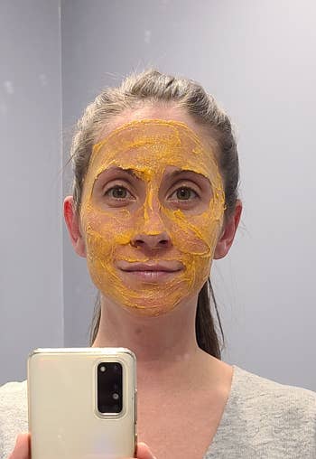 Person applying a facial mask, taking a selfie. 