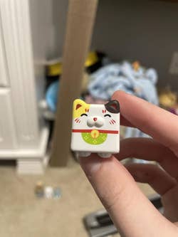 A person holds a small, cube-shaped figurine