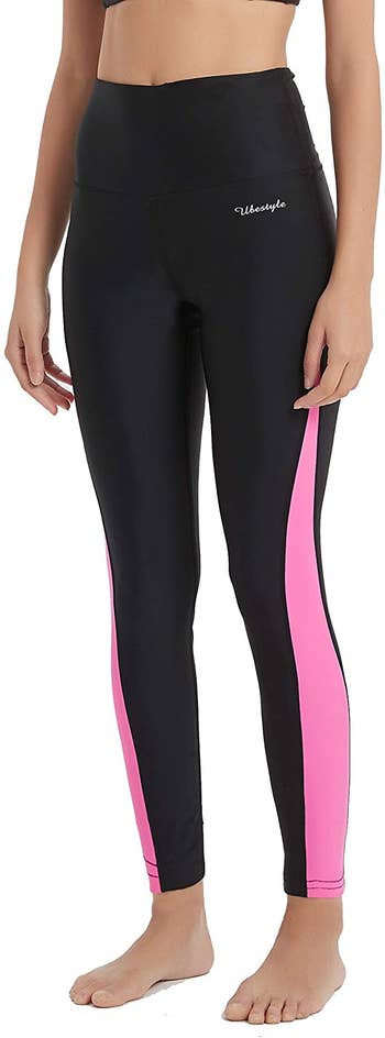 model in black high-waist leggings with pink stripe down sides of leg