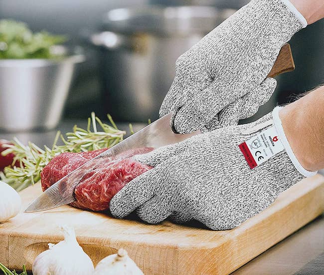 Model wearing grey gloves while cutting meat 