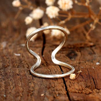 The two loop silver ring resting on a table 
