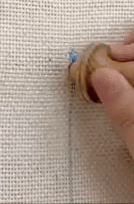 model using a needle punch to make thread lines in an embroidery square 