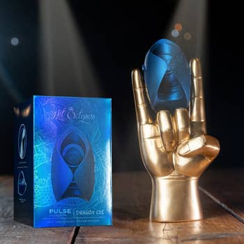 Golden manus sculpture holding a bluish product. Box labeled