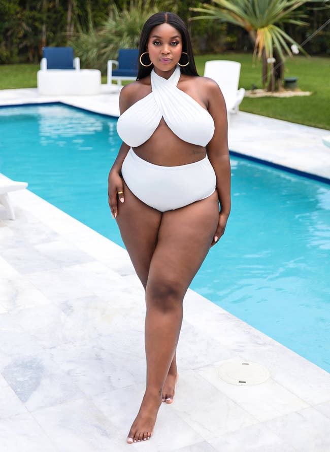 model posing in white halter bikini by a pool