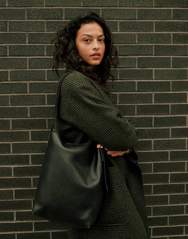model carrying the black leather bucket bag