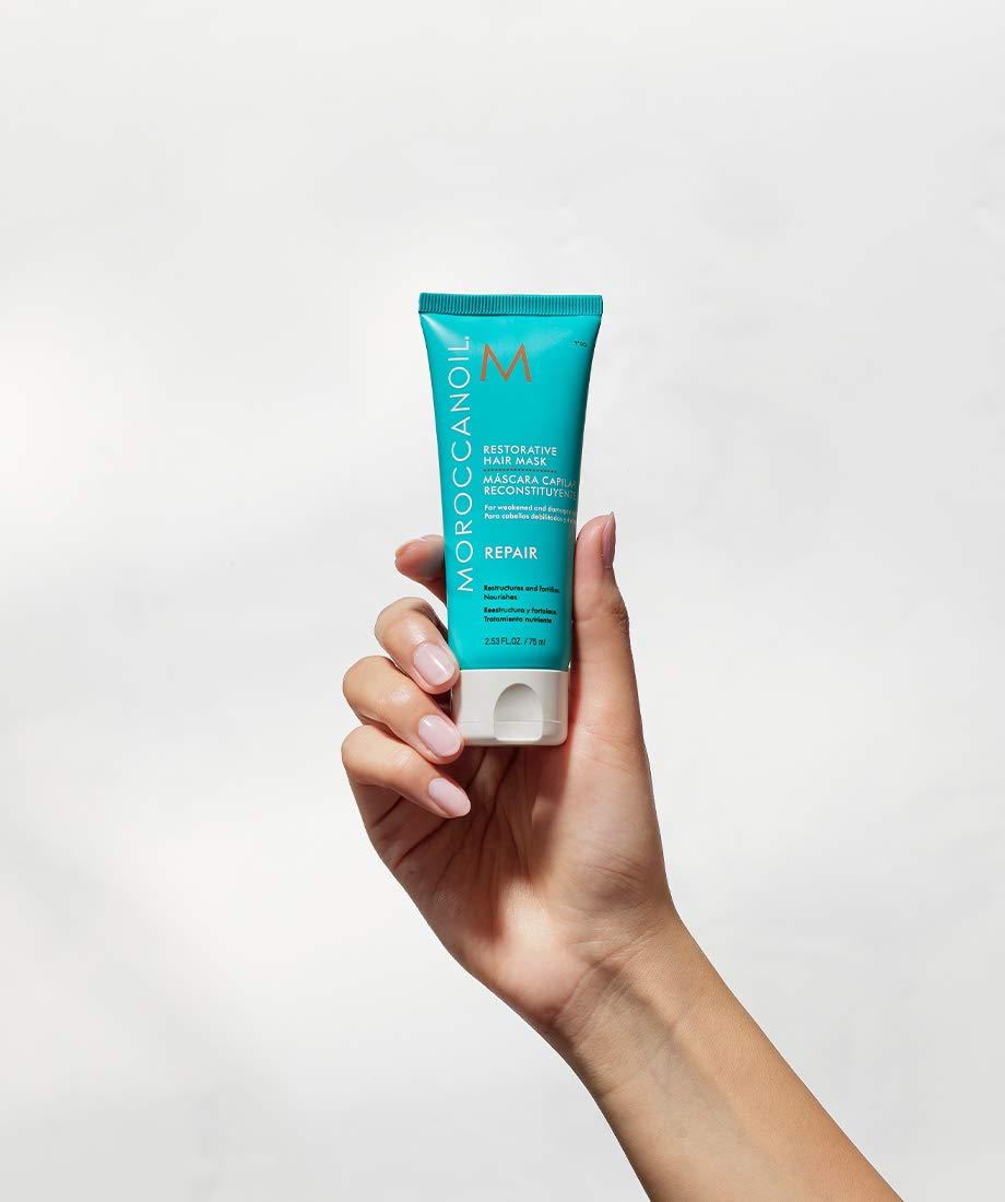 Hand holding a conduit  of Moroccanoil Restorative Hair Mask, highlighting hairsbreadth  repair benefits, perfect  for nonfiction  categorized arsenic  Shopping