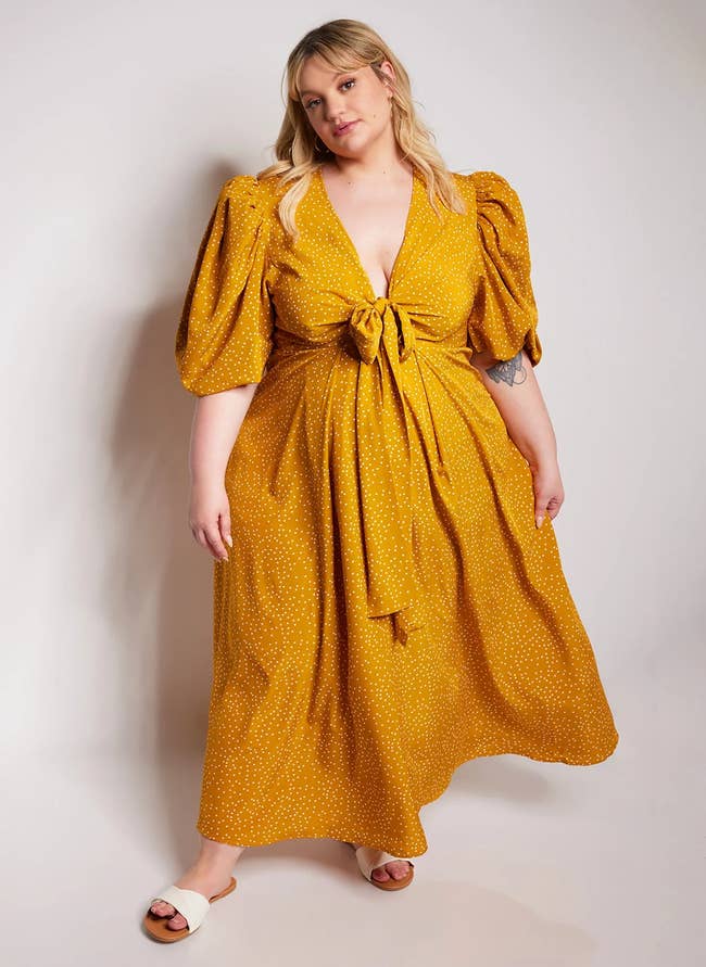 plus-size model wearing mustard yellow maxi dress with white polka dot pattern and a tie front