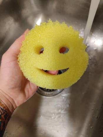 reviewer holding round yellow smiley face sponge