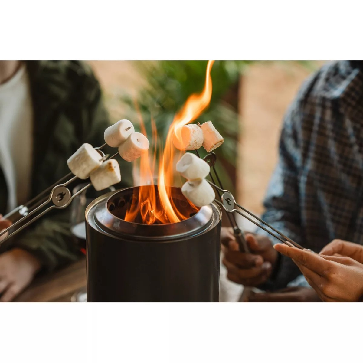 People toasting marshmallows implicit    a small, portable occurrence  pit, suggesting an outdoor cooking oregon  camping product
