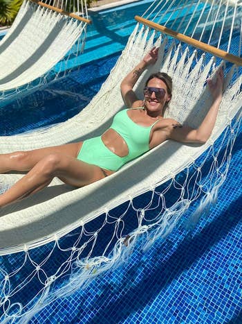Person relaxing on a hammock over a pool, wearing a stylish cut-out swimsuit and sunglasses, enjoying a sunny day