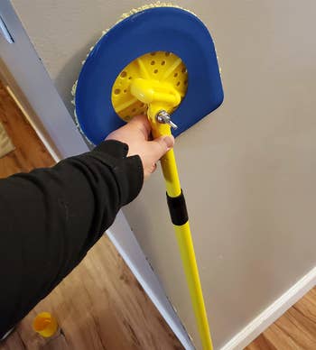 Reviewer holding up the yellow and blue handled mop 