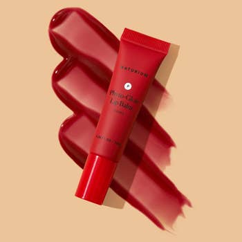 the tube of balm on top of a swatch of the red shade
