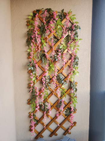 reviewer's faux pink wisteria hanging on a wooden fixture on a balcony 
