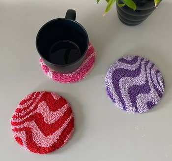 the round wavy coasters in different colors, with one holding a mug