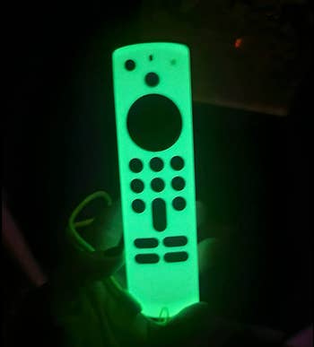 A reviewer's green silicone case glowing over a Fire Stick remote 